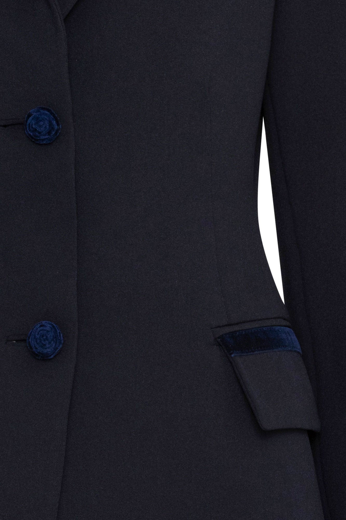 The Blazer Botón Rosa — close-up of center front placket showing three navy velvet rose-embossed buttons and hip flap pocket with single velvet rose button, with navy velvet trim cuff visible at sleeve hem