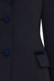 The Blazer Botón Rosa — close-up of center front placket showing three navy velvet rose-embossed buttons and hip flap pocket with single velvet rose button, with navy velvet trim cuff visible at sleeve hem