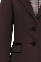 Blazer Juan Cintas Botón Rosa Café — close-up of front showing notched lapel with multicolor Prince of Wales check lining visible inside, two large domed brown buttons on center front, and hip flap pocket with narrow dark brown velvet ribbon trim along pocket edge