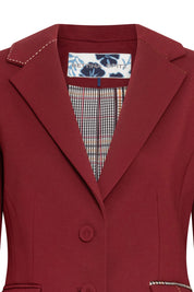 Blazer Juan PP Argollas Vino — close-up of front lapel and interior showing notched lapel with cream hand topstitch, Prince of Wales check lining in cream, brown, and black visible inside lapel opening, Bettina Spitz woven label on floral-print ground at center back neckline, and two-button front closure