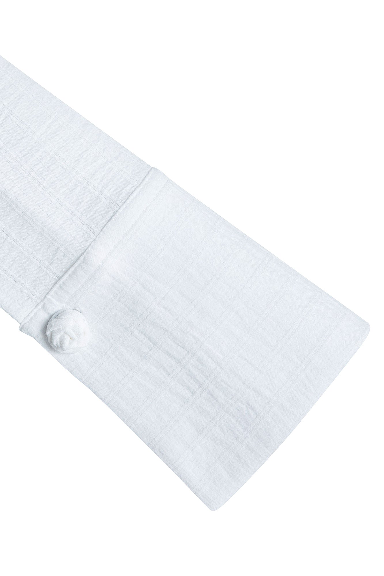 Close-up of wide ivory blouse cuff with a tonal rose-shaped fastening