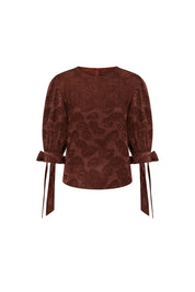The Blusa Manga Puff Mono Chocolate Brown Jacquard Blouse — full front view showing fitted cropped silhouette with round jewel neckline, three-quarter puff sleeves gathering from shoulder and tying in satin ribbon bow at each wrist cuff