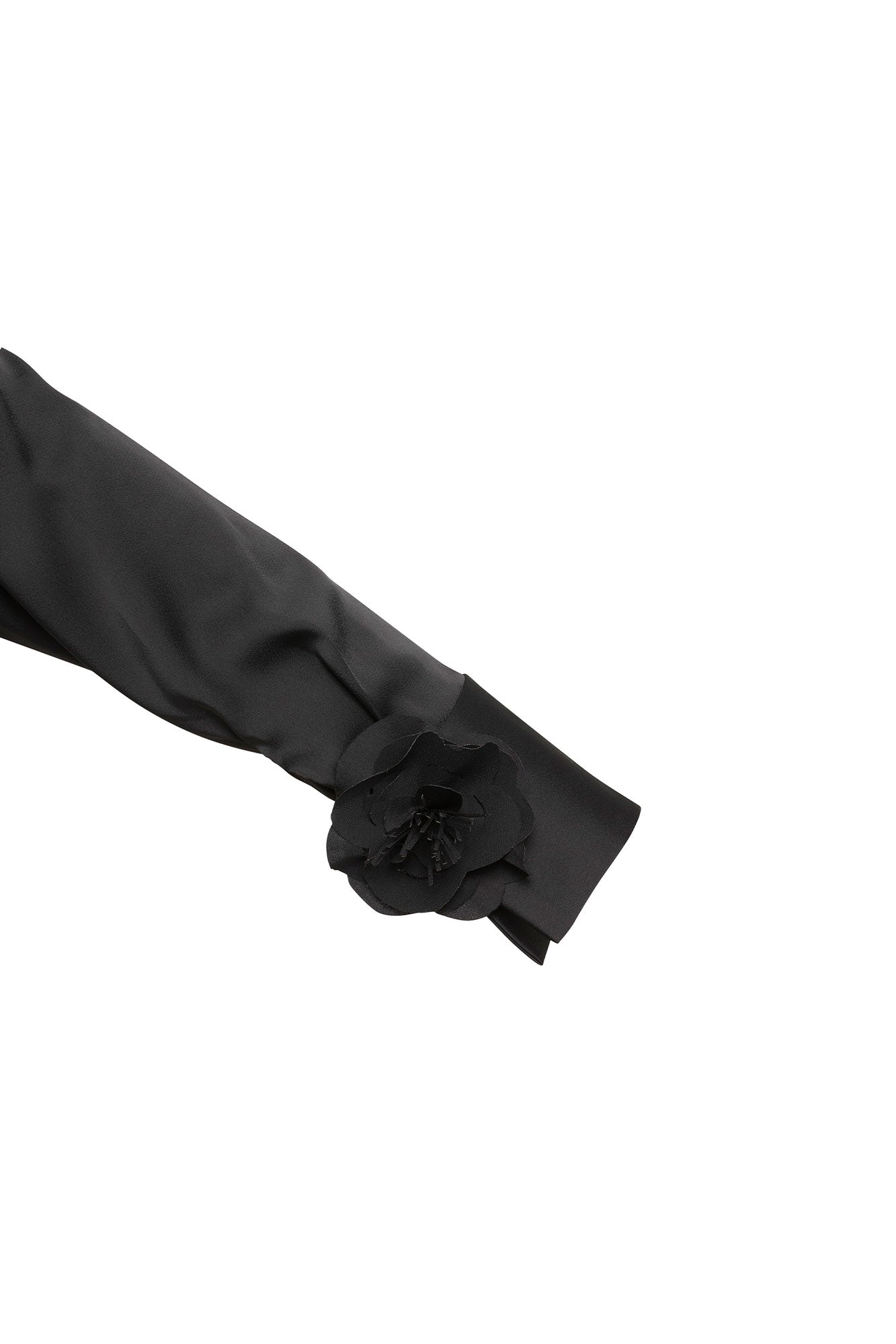 The Verónica Black Satin Blouse — close-up of sculptural 3D black rose with feathered petals at wide cuff