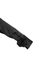 The Verónica Black Satin Blouse — close-up of sculptural 3D black rose with feathered petals at wide cuff