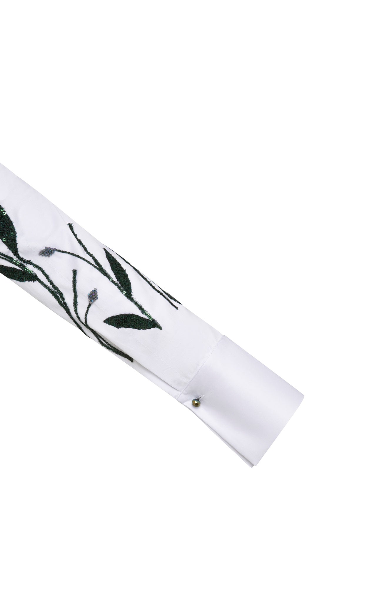 The Sol Flor White Shirt — close-up of wide cuff with dark green leaf embroidery and silver ball button