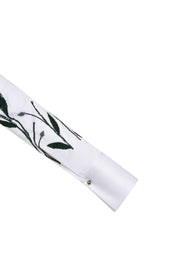 The Sol Flor White Shirt — close-up of wide cuff with dark green leaf embroidery and silver ball button
