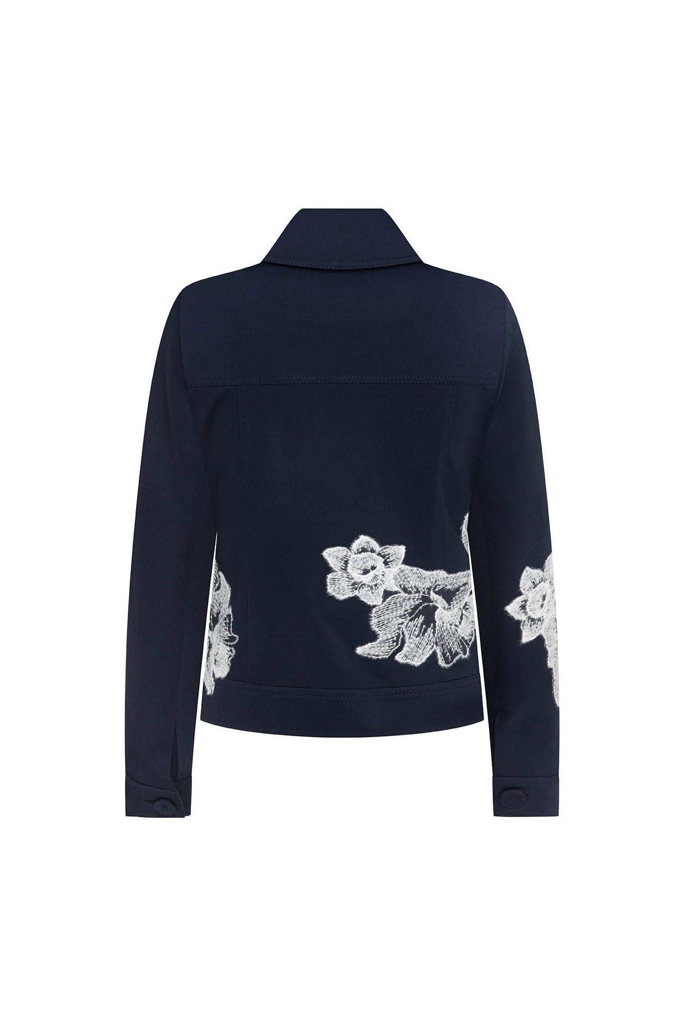The Chaqueta Jean Flor Hilo Navy — full back view showing horizontal seam band at lower back and clusters of large-scale white botanical embroidery covering lower back panels against deep navy crepe, with single navy button at each cuff