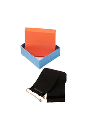 The Terciopelo Belt — presented folded beside the Bettina Spitz signature gift box with orange lid and blue base, gold bar closure visible with engraved label