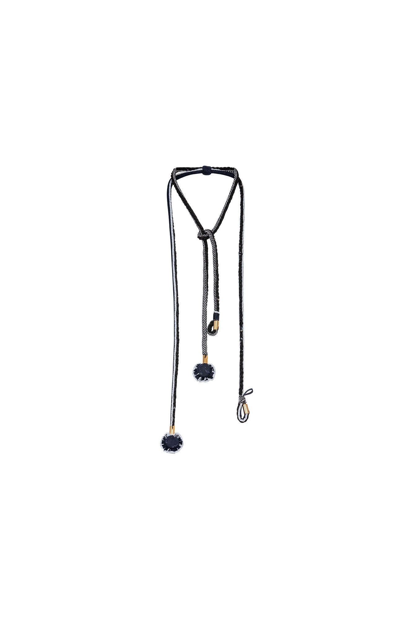 The Collar Cordón Doble Braided Lariat Necklace — full view showing looped top with knotted closure and two asymmetric drops in black and silver herringbone braid tipped with gold aglets and black pompom rosettes
