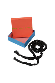 Black lace and bead necklace with fringed ends beside an orange and blue Bettina Spitz box