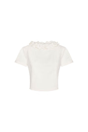Crop Manguita CR Flor Ivory — full front view showing fitted ivory cropped short-sleeve top with hand-applied 3D fabric flower collar of layered multi-petal ivory blooms covering entire neckline from shoulder to shoulder in a continuous botanical garland