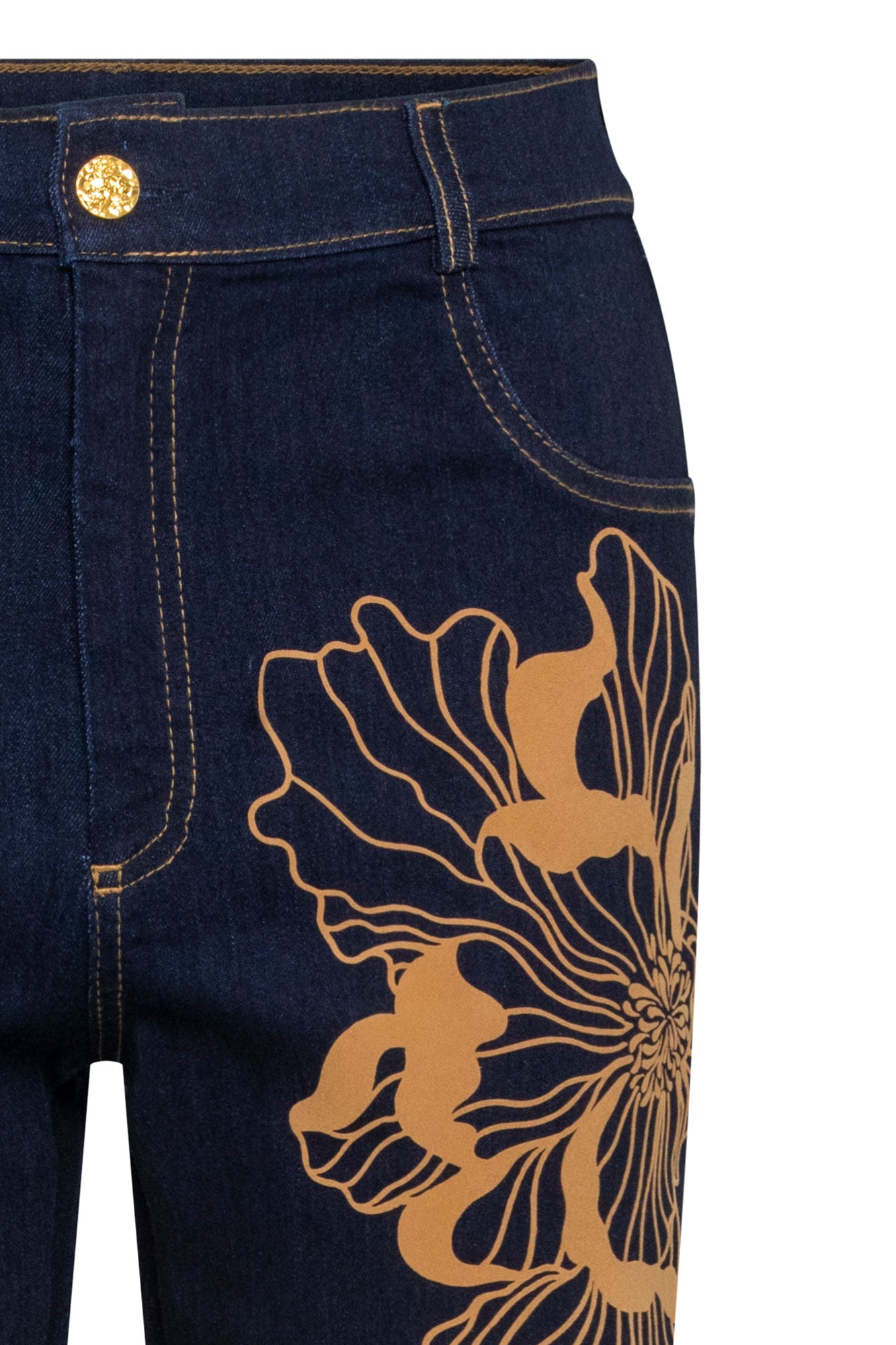 The Jean Recto Flor Maxi — close-up of caramel gold peony embroidery at hip and thigh showing combination of filled satin-stitch petals and fine outline-only petals in warm gold thread on dark navy denim with gold embossed button