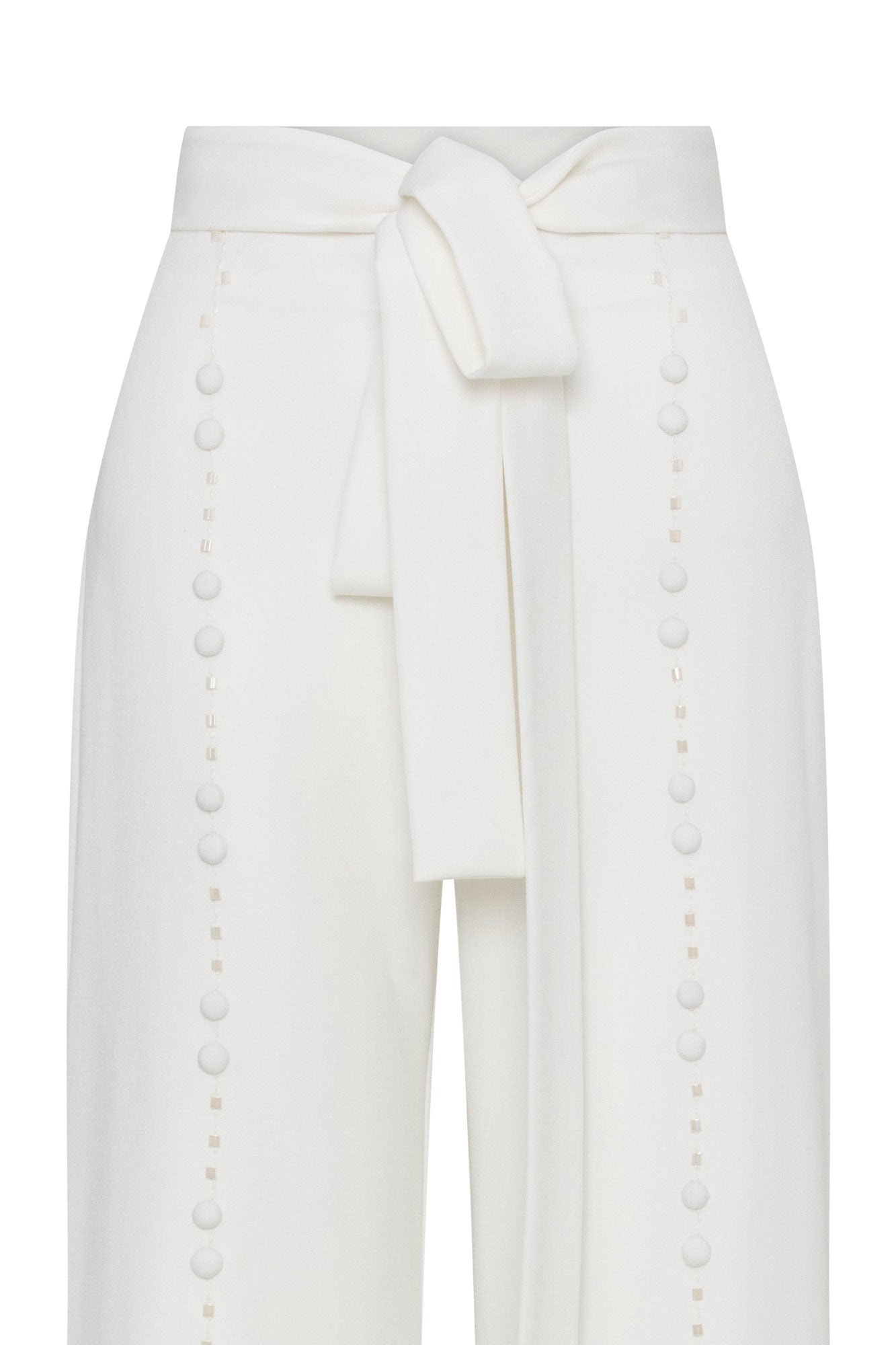 Close-up of ivory trousers showing wide tie belt and vertical tonal button detailing