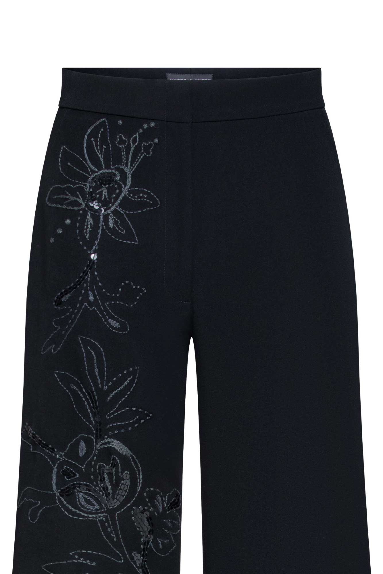 The Gaby Black Wide-Leg Trousers — close-up of hand-embroidered floral vine with tonal black thread, cutwork openwork petals, crystal accents and acrylic ring detail