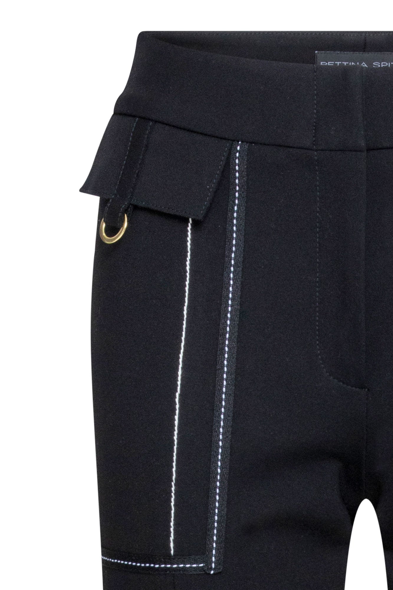 The Patch Campana — close-up of front hip patch pocket with fold-over flap, Bettina Spitz label at waistband, and white contrast topstitching detail against black structured fabric