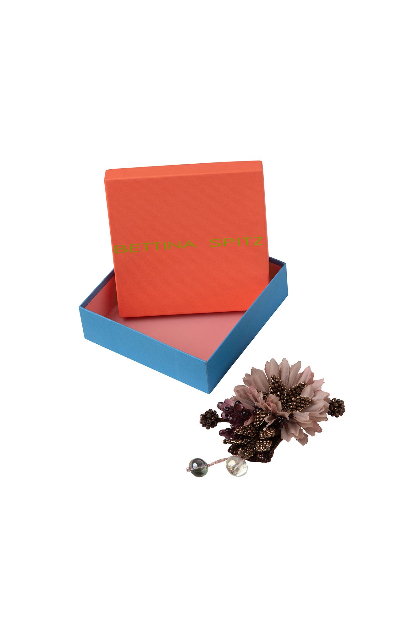 Floral brooch with bead clusters and translucent drops beside an orange and blue Bettina Spitz box