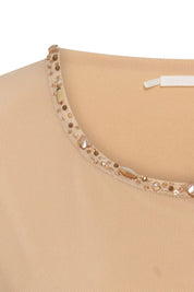 The Top Mallita Cuello Brillos Arena — close-up of scoop neckline showing single continuous row of mixed gold and champagne faceted crystal studs in different sizes and cuts hand-applied along entire neckline edge against sand stretch knit fabric