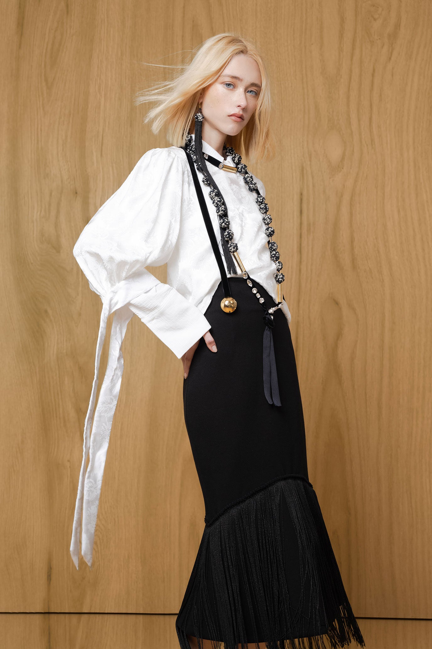 Full-length model view of Bettina Spitz black fringe midi skirt styled with a white blouse and black heels