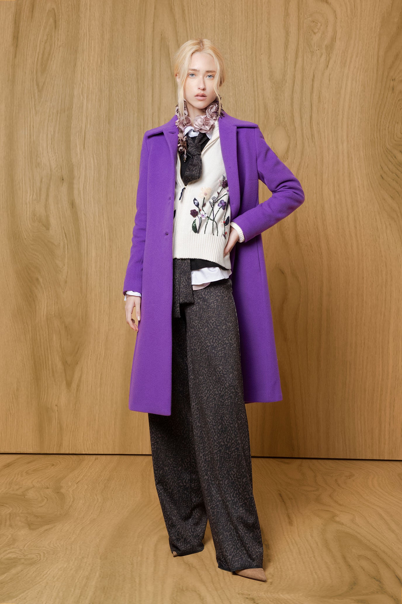 Model wearing Bettina Spitz chocolate leopard-pattern wide straight-leg trousers with an ivory top and purple coat