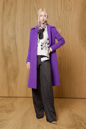 Model wearing Bettina Spitz chocolate leopard-pattern wide straight-leg trousers with an ivory top and purple coat