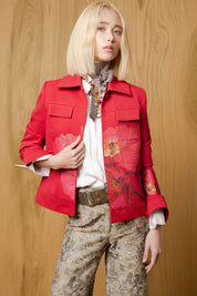 Model wearing Bettina Spitz red Cayena jacket with pointed collar, flap chest pockets and large floral motifs over a white shirt